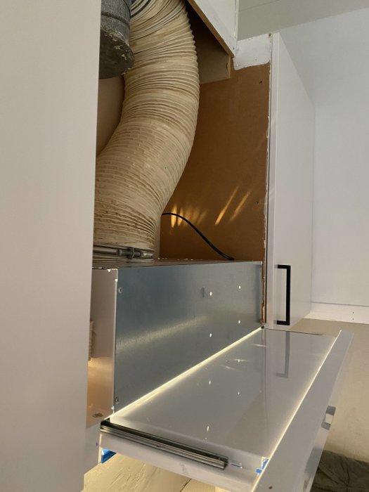 Installation av köksfläkt med synlig ventilationsrör och oavslutad kringbyggnad.