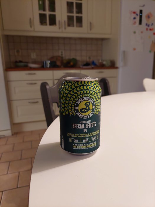 Alkoholfri ölburk Brooklyn Special Effects IPA på ett vitt köksbord, suddig bakgrund med köksskåp.