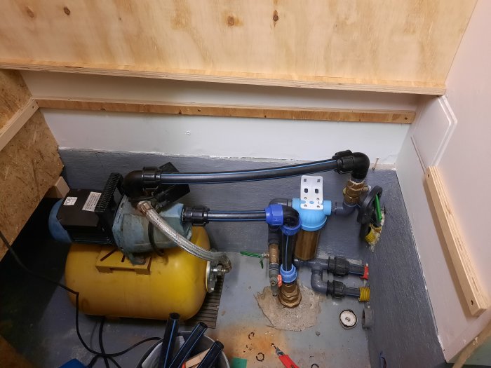 Installationsvy av sugledning i golvet kopplad till pump och filter med unionkopplingar i ett litet utrymme.
