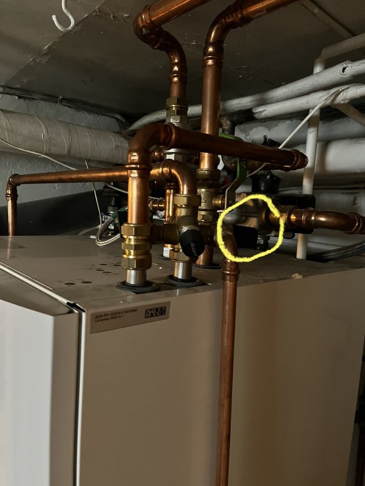 Kopparledningar och komponenter på en uppvärmningsanläggning, markerad del med gul ring.