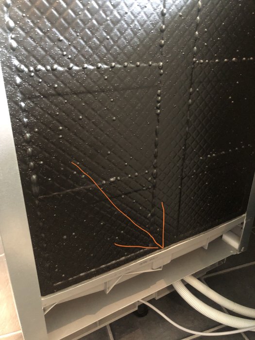 Vattendroppar på ett svart diskskydd med en orange pil som pekar mot en tänkt läcka längs kanten.
