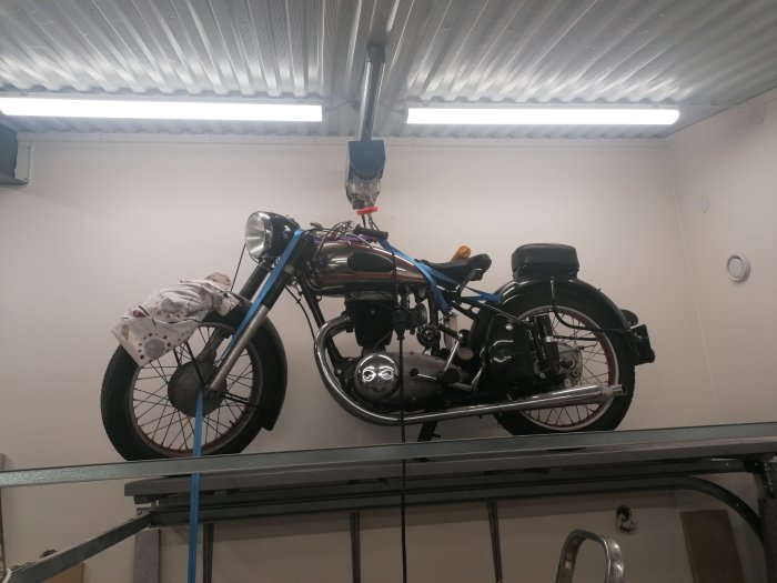 Gamla motorcykeln monterad på väggen i ett garage, med reflektion av personligt värde.