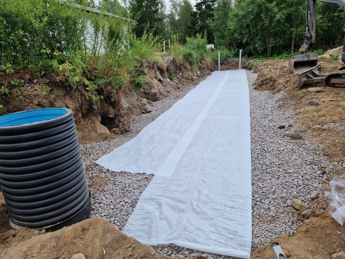 Markförstärkning med grus och installerad markduk längs en grävd dräneringsdike.