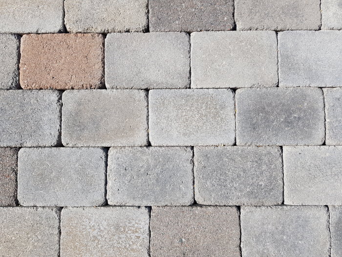 Olika nyanser av gråa och brun stenläggningsplattor lagda i mönster på en yta.