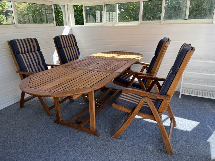 Trägårdsmöbler bestående av ett bord och fyra stolar på en veranda.