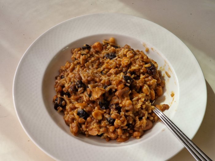 Tallrik med risotto med svamp och pumpa, belyst av solen, sedd uppifrån.