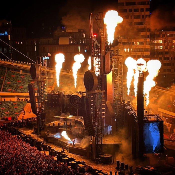 Konsertscen med Rammstein på Ullevi med eldeffekter, omgiven av publik och stadsbebyggelse i bakgrunden.