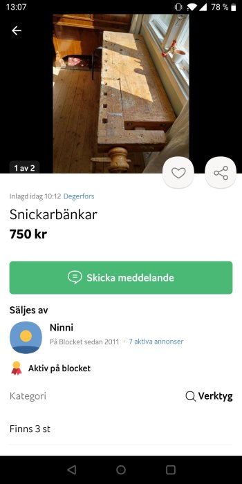 Delvis vitmålad gammal snickarbänk i trä mot en fönsterbakgrund i ett ljust rum.