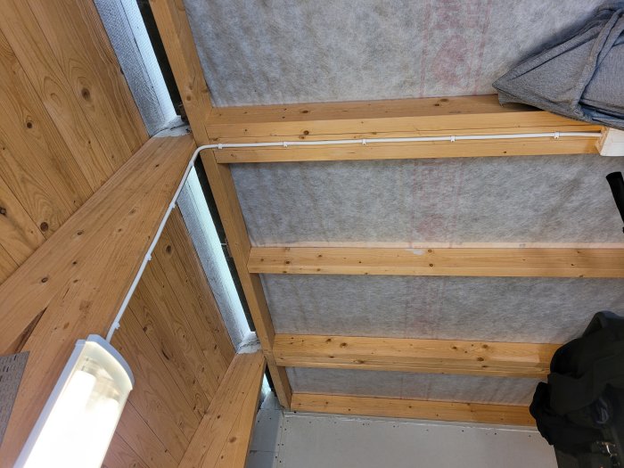 Innertak under konstruktion med synliga träbalkar och isoleringsmaterial i ett byggprojekt.