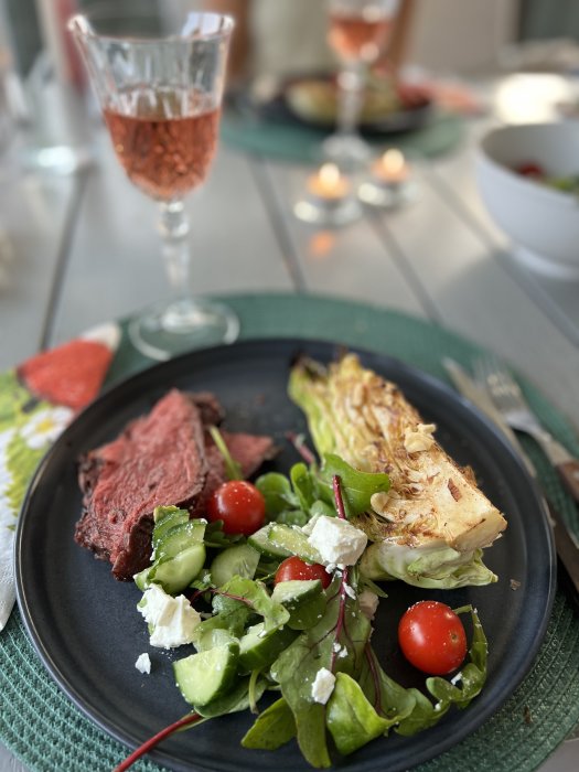 Närbild av grillad mat på en tallrik med skivad stek, grillad sallad, och en sallad med fetaost.