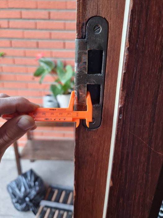 Mätning av gammalt dörrlåsbleck med snedvinkel på en dörrkarm.