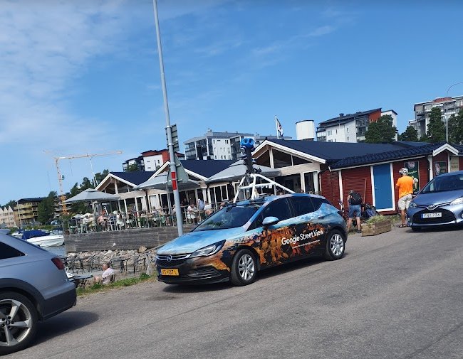 Google Street View-bil med kamerautrustning kör på gata under solig himmel.