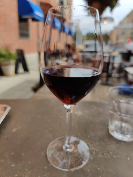 Ett glas fyllt med röd Grenache-vin på ett bord utomhus.