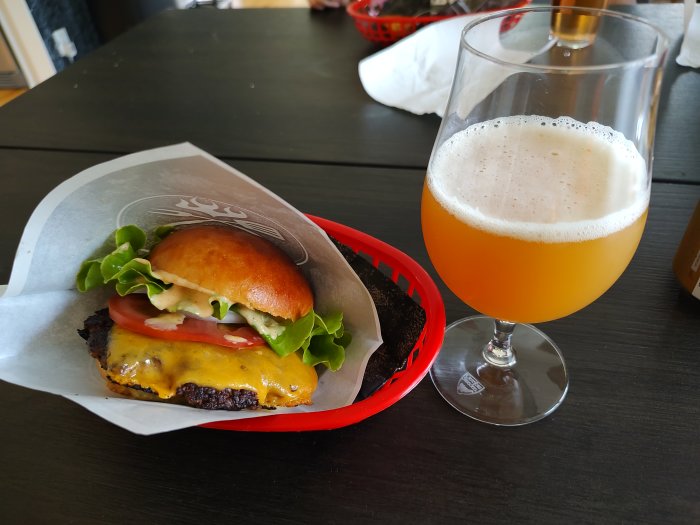 Cheeseburger på röd bricka bredvid ett glas Amazing Haze öl.