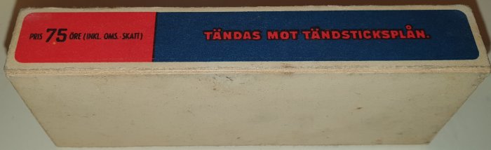 Gammal tändsticksask med texten "PRIS 75 ÖRE inkl. OMS." och instruktion "TÄNDAS MOT TÄNDSTICKSPLÅN.