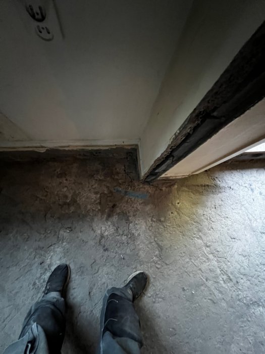 Arbetsklädda fötter och markerat område för borrning av ventilationshål på ett betonggolv.