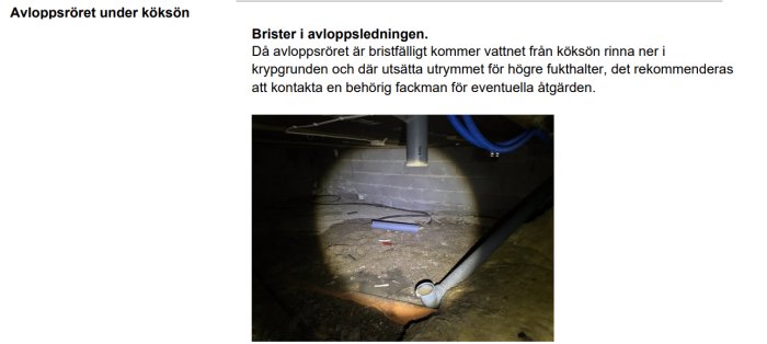 Avloppsrör och kablar i en fuktig krypgrund belysta av ficklampa.