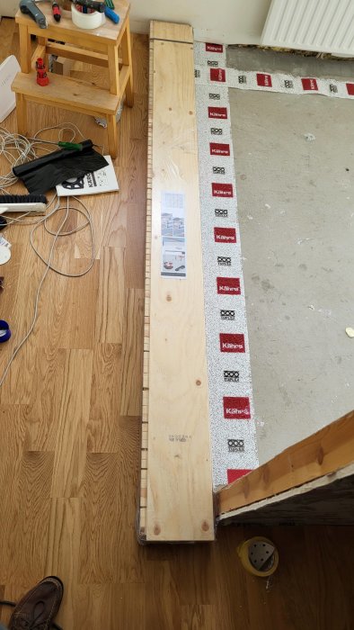 Delvis lagt ekparkettgolv bredvid ofärdigt betonggolv med verktyg och byggmaterial.