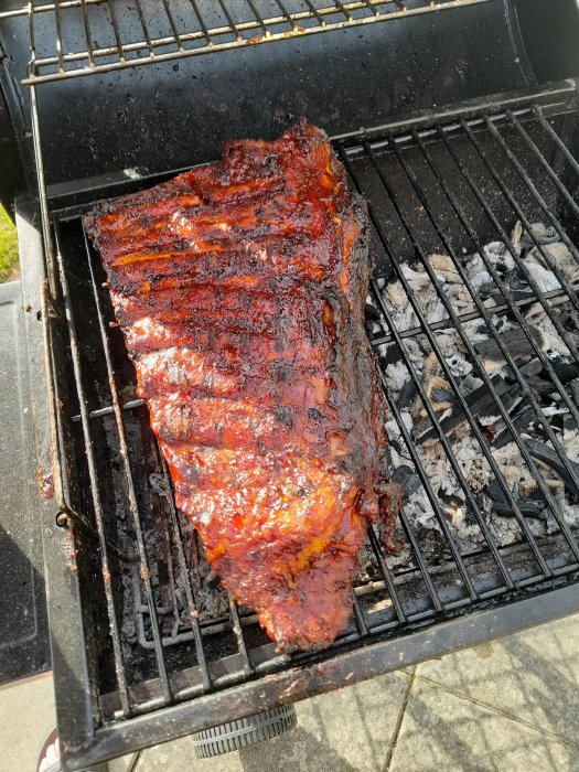 Grillade revben tillagade på indirekt värme, glansiga av marinad och nära färdiga.