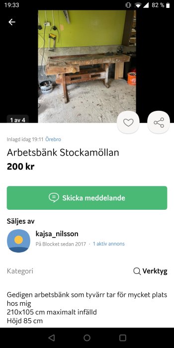 Använd arbetsbänk i trä framför gul vägg med diverse verktyg och en öppen färgburk på golvet.