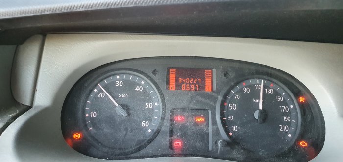 Bilens instrumentbräda med varningslampor tända och en trippmätare visande 340227 km.