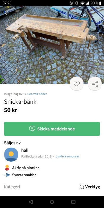 Gammal snickarbänk i trä med skruvstäd till salu på gatustenar.