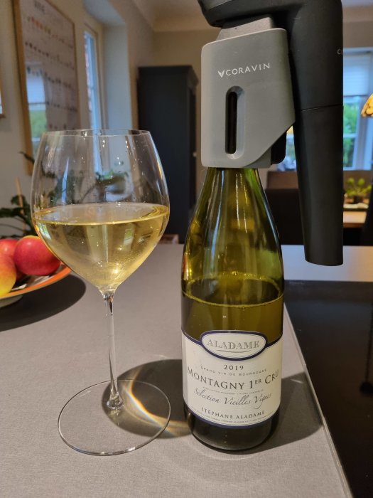 Glas med chardonnay och en flaska Montagny 1er Cru från Bourgogne med Coravin-system.