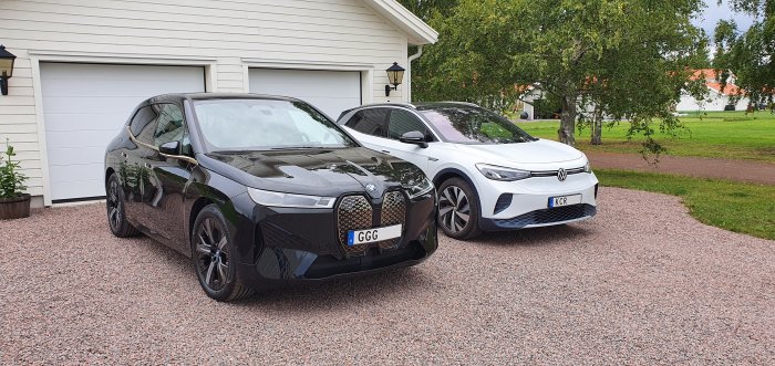 En BMW iX och en Volkswagen ID.4 parkerade på en grusuppfart framför en vit garageport.