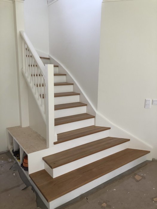 Nybyggd trappa med vitmålade sidor och mörkt trä för trappstegen.