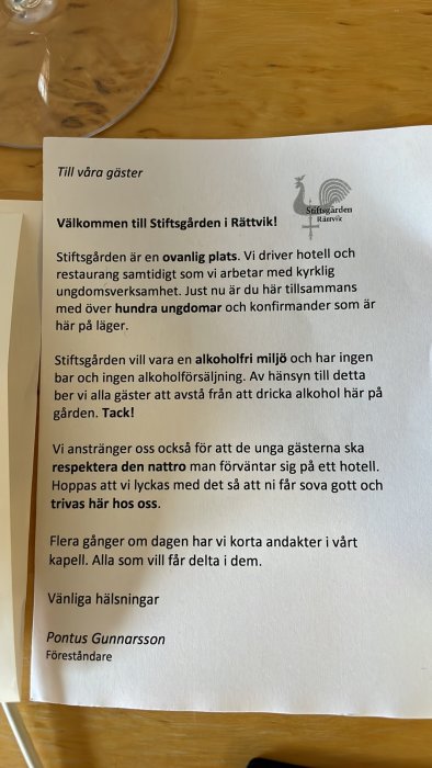 Välkomstbrev på ett bord med text om Stiftsgården i Rättviks policy om alkoholfri miljö och andakter.