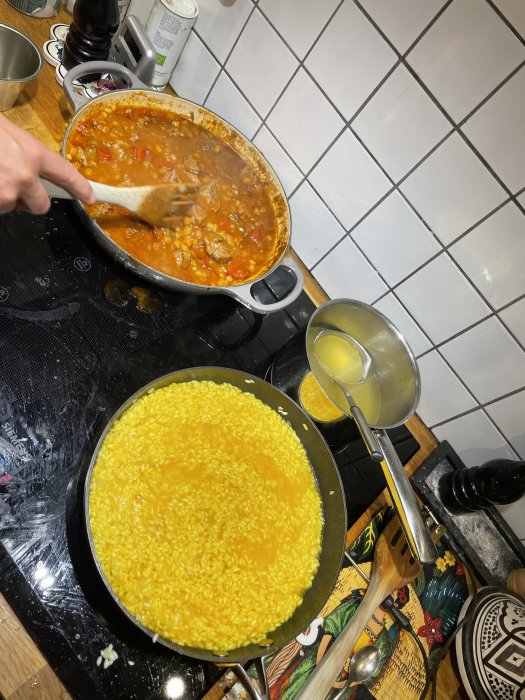 Tillagning av ossobuco med kalvhögrev istället för lägg, bredvid en panna med risotto på ett köksspishäll.