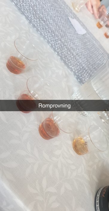 Glas med olika sorters rom ordnat för provsmakning på ett bord med vit duk.