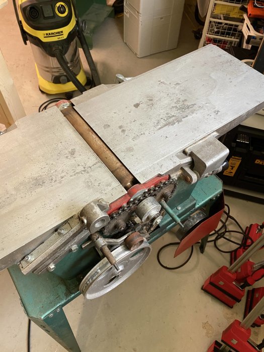 Verktygsmaskin med oljefläckar och rost på riktborden, närbild på kutterskyddet och riktbordets aluminiumyta.