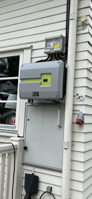 Elcentral och omvandlare installerade på husvägg för solpanelssystem.