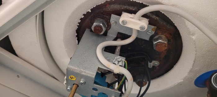 Rostig insida av en apparat med ventiler, kablar, och mekaniska komponenter.