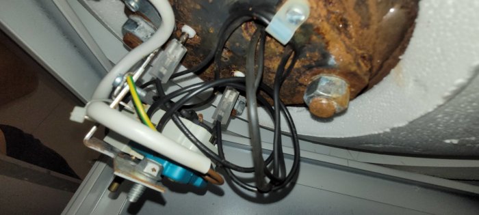 Värmepanna med synlig korrosion och flera anslutna kablar, inklusive gul/grön jordkabel.