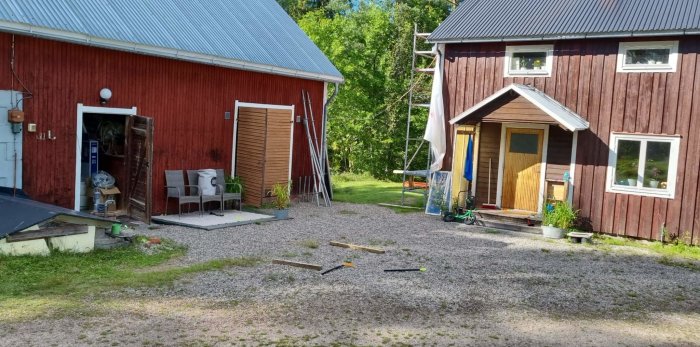 Rödfärgad lada till vänster och större trähus med stege stående mot fasaden.