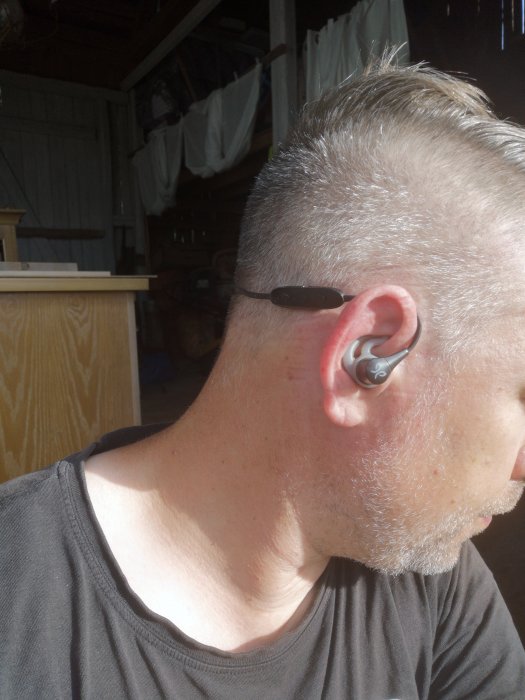 Person med Jaybird x4 hörlurar i örat och sladd bakom örat, samt en tydlig svettband.
