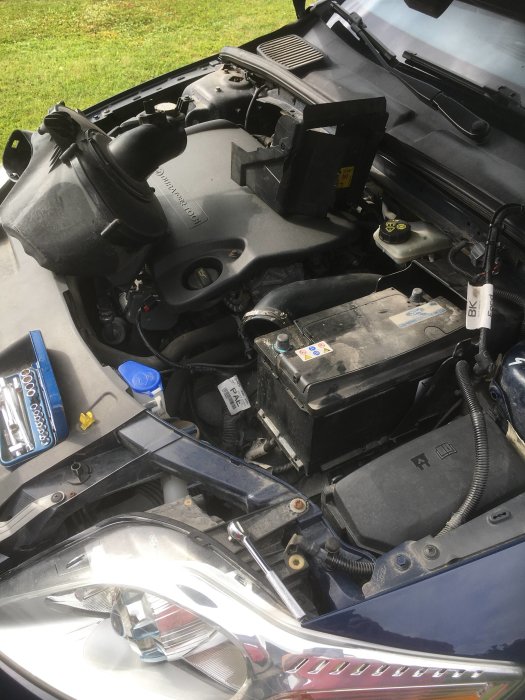 Motorns insida i en bil med fokus på det nyinstallerade bilbatteriet och öppet verktygsset.