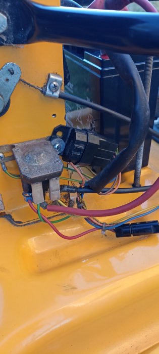 Elektrisk installation med kablar och komponenter på ett gulaktigt fordon.