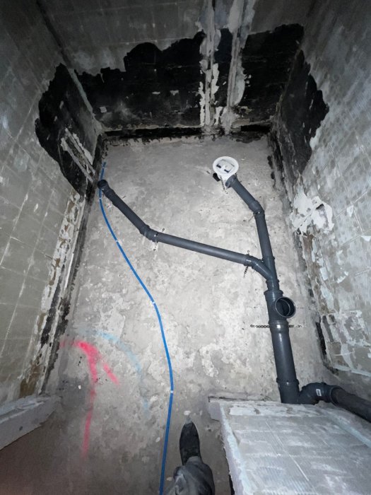 Installation av avloppsrör med 45° språng i en källarrenovering, golv och väggar syns.