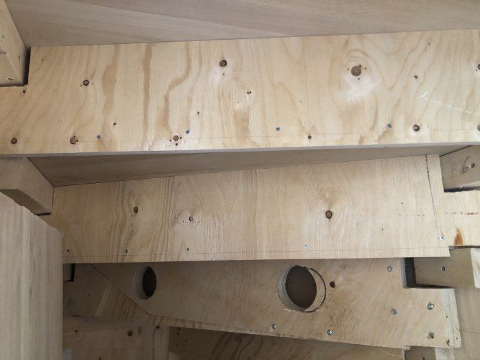 Obyggd trappkonstruktion med plywood, reglar och skruvhål under monteringsprocessen.