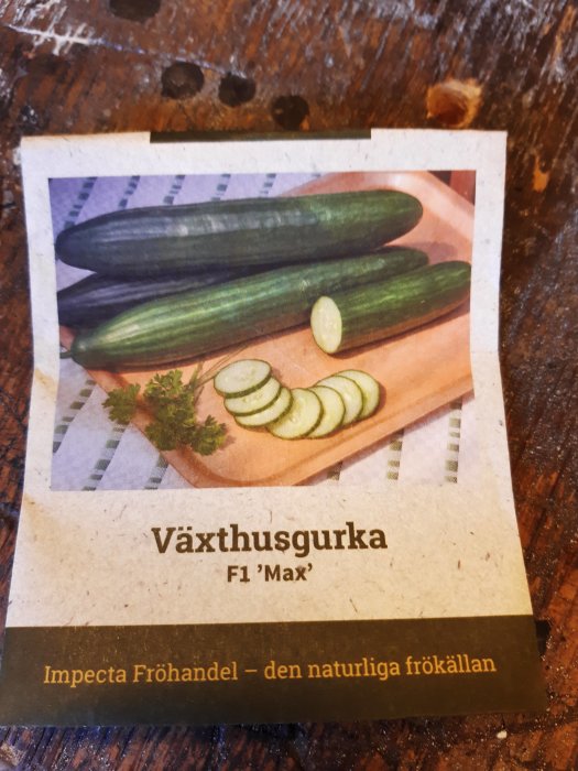Fröpåse för Växthusgurka F1 'Max' med bild på hela gurkor och skivade på träbakgrund.