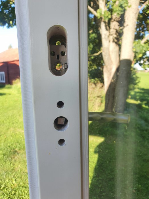 Närbild av en vit dörrkarm med ett dörrlåsets insidesmekanism och hål för installation.