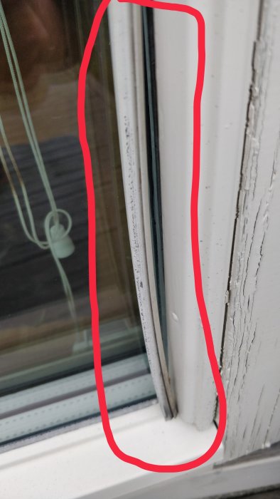 Närbild av en fönsterkarm med slitage och avflagningar markerade med röd cirkel
