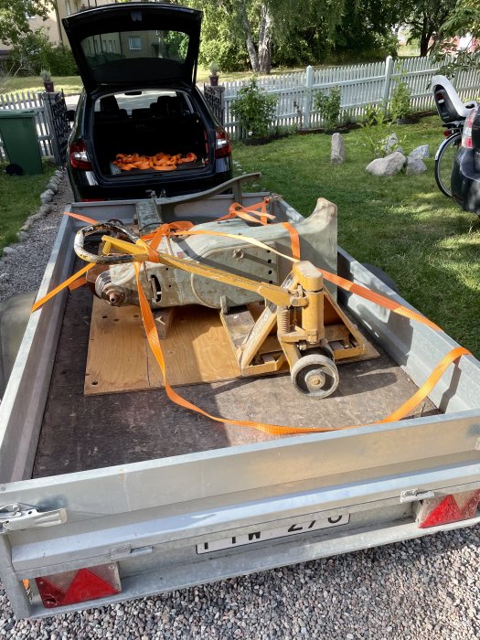 En gammal svarv säkrad med spännband på en släpvagn, redo för transport.