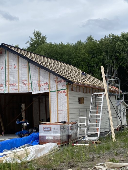 Nybyggt garage med takstolar och väderbarriär, utan garageport och hängrännor.