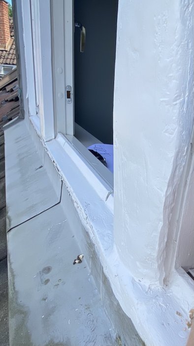 Vitt fönsterkarm i behov av underhåll med flagande färg och synlig trästruktur, öppet mot mörkt rum.