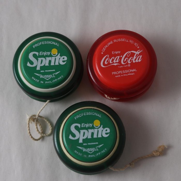 Tre jojos med Coca-Cola och Sprite-logotyper, två gröna för Sprite och en röd för Coca-Cola.