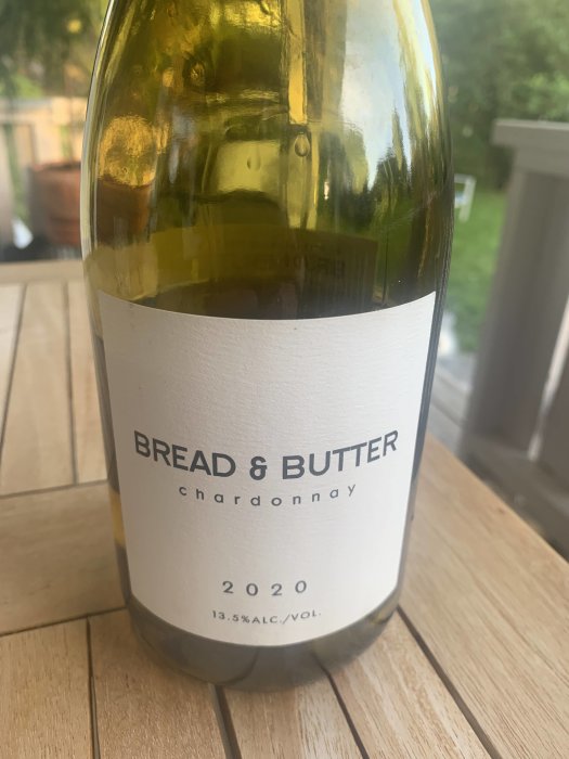 Flaska Bread & Butter Chardonnay 2020 på ett träbord, vinet beskrivs som rund med vaniljton.